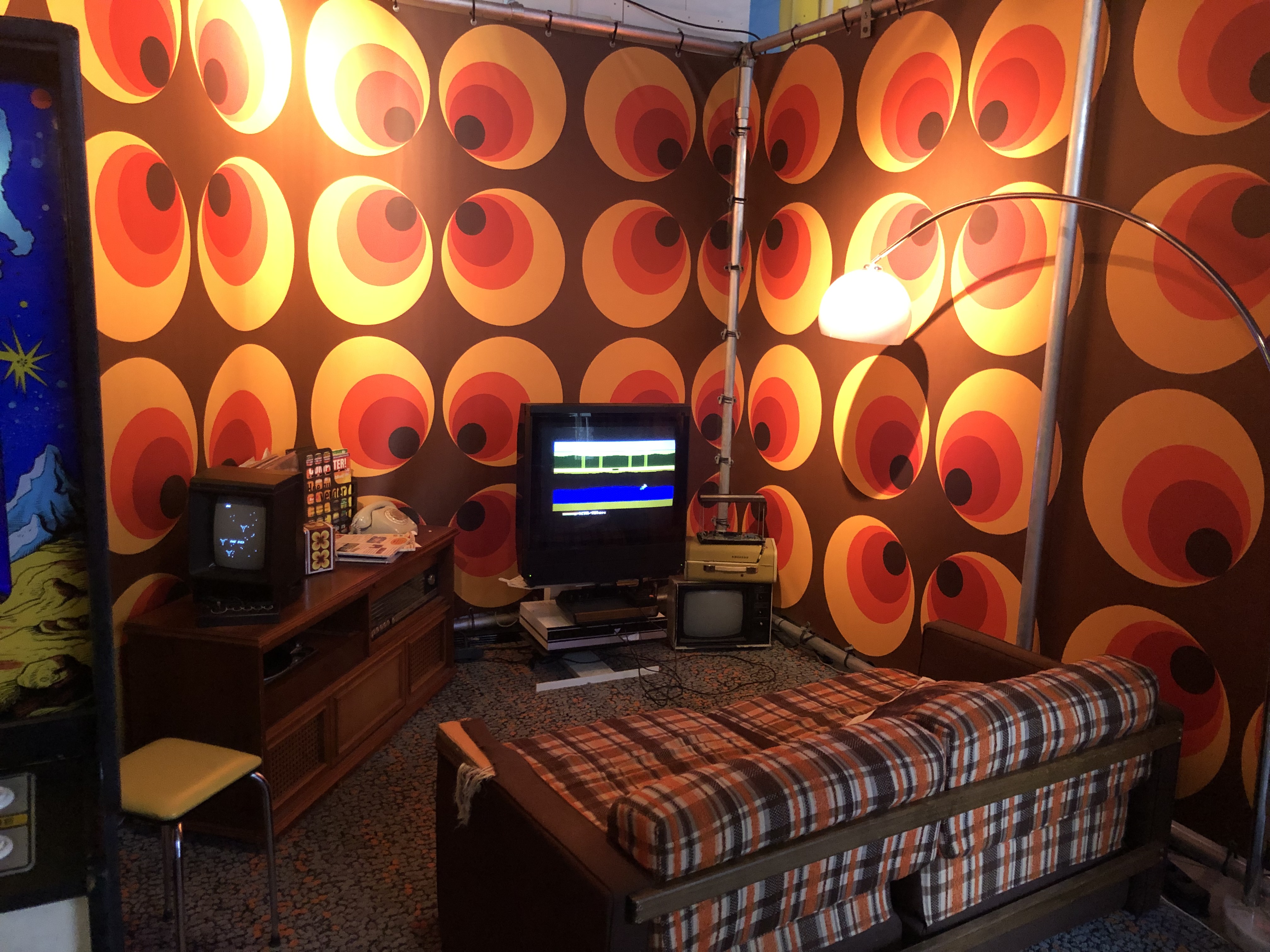 foot van een kamer van het museum, er staat een bank en een oude tv, de kamer heeft oranje behang met een patroontje